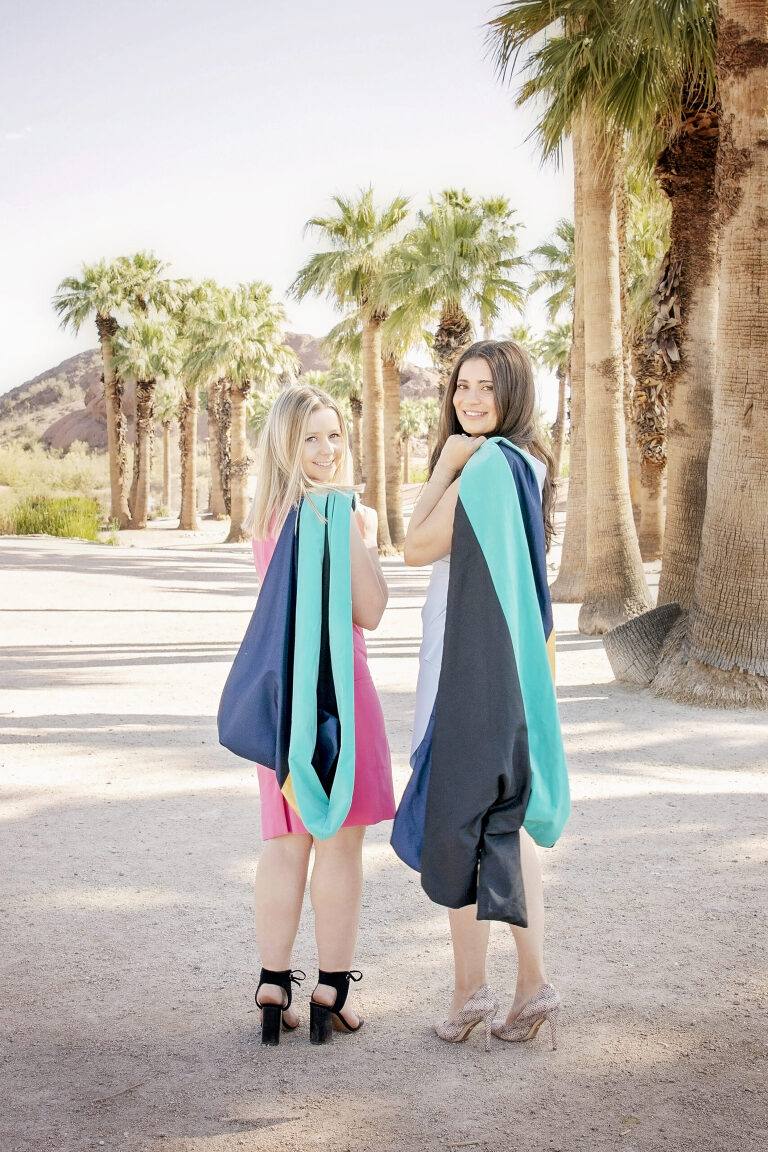 Two female college graduates looking back in front of palm trees photo in Phoenix, Arizona