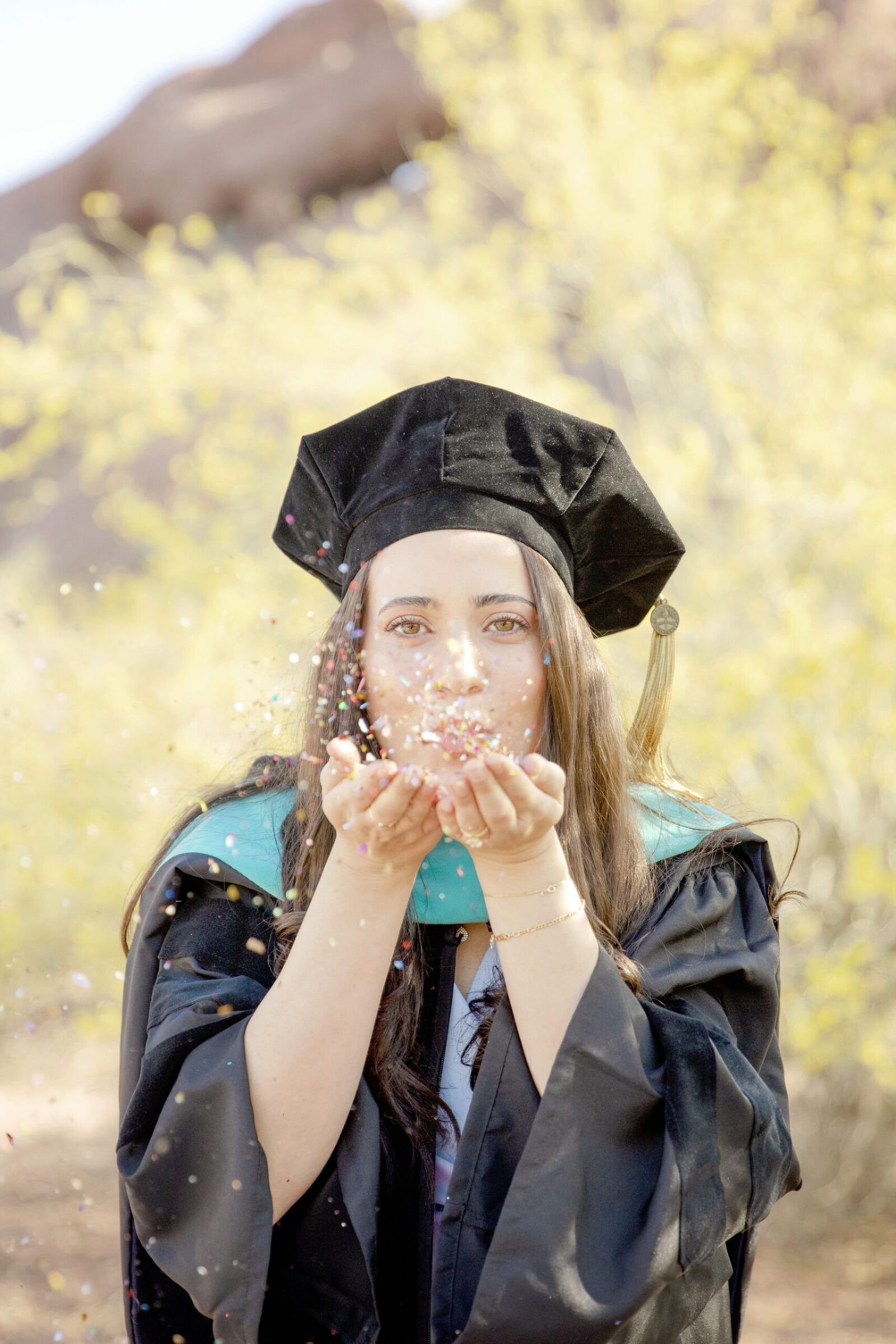 Female college graduate blowing confetti in Phoenix, Arizona