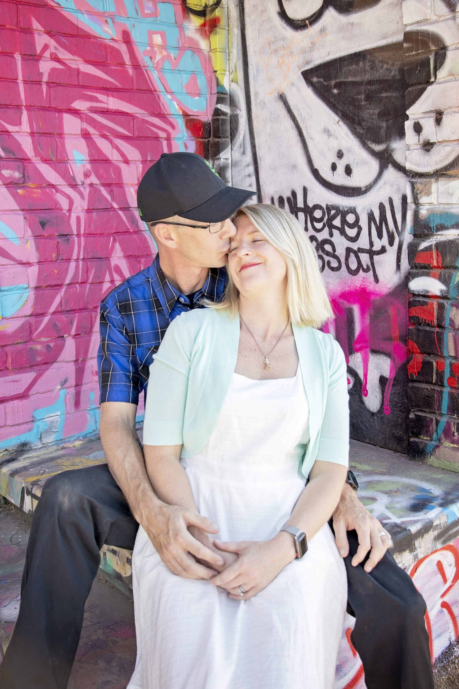 Couple Photo man kissing wife's cheek in front of street out Downtown Phoenix, Arizona
