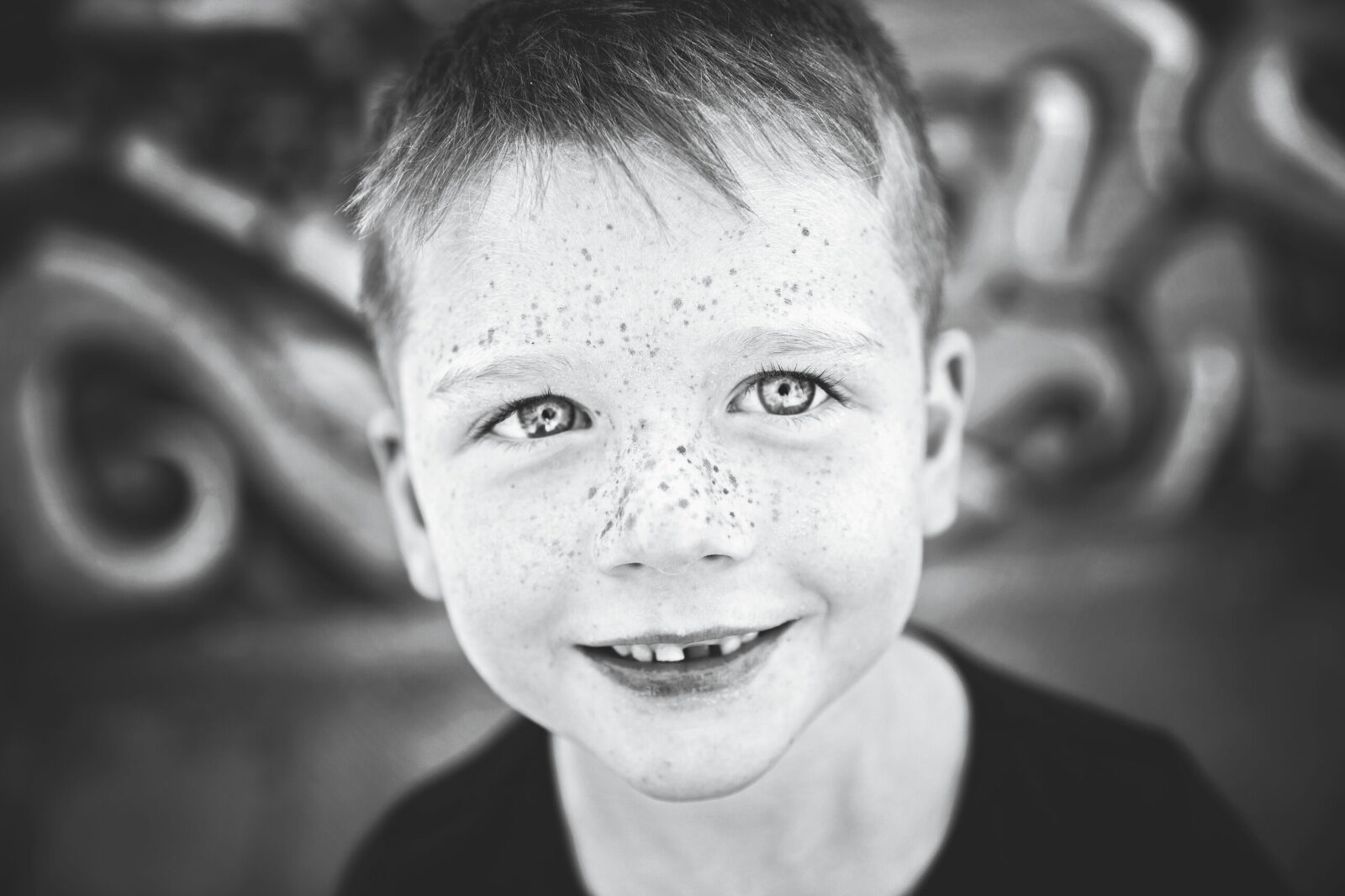 Freckled school age boy with missing teeth black and white closeup photo in phoenix, Arizona